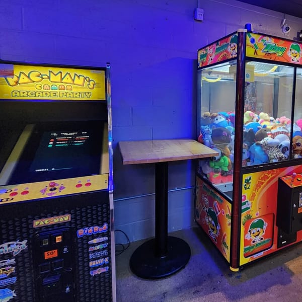 A Pac-Man arcade game and a claw machine filled with plush toys at Loose Ends Brewery.