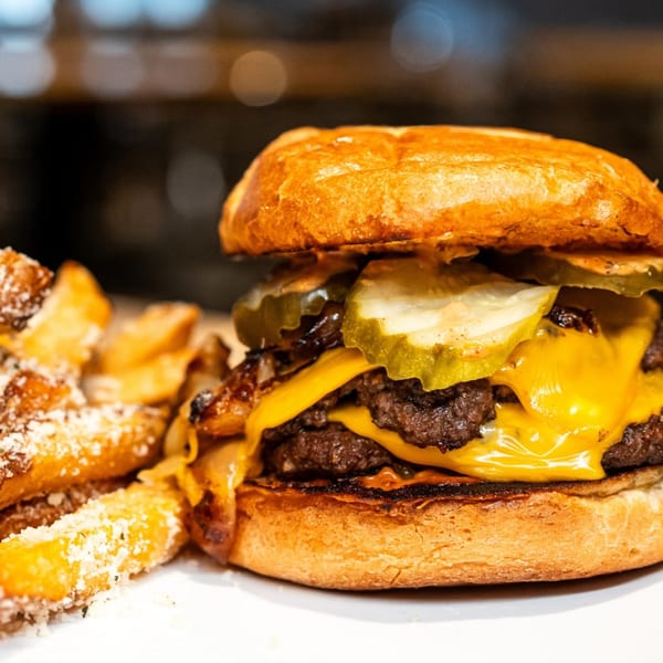 A Loose Ends Brewery double cheeseburger with pickles and caramelized onions, served with fries.
